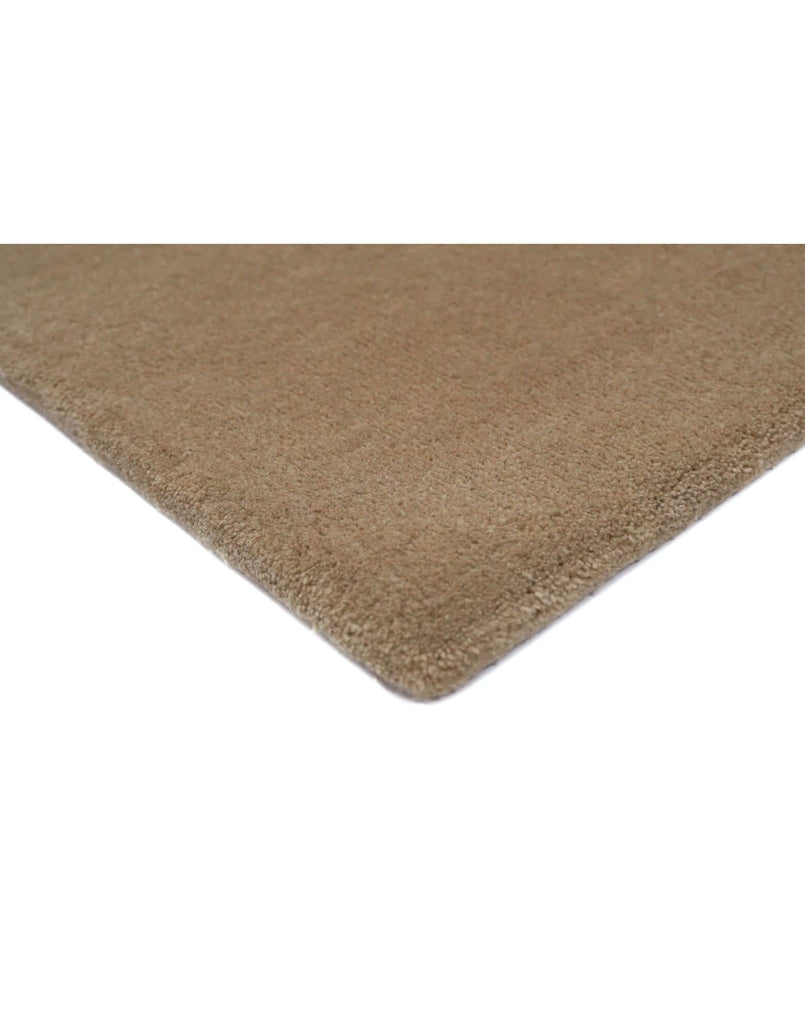 Close-up of I C O N - L A T T E rug edge, showcasing the luxurious texture of New Zealand wool craftsmanship.